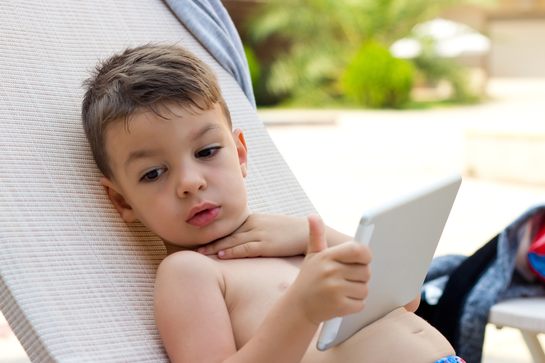 Cute little boy using laptop while in swimming pool pool